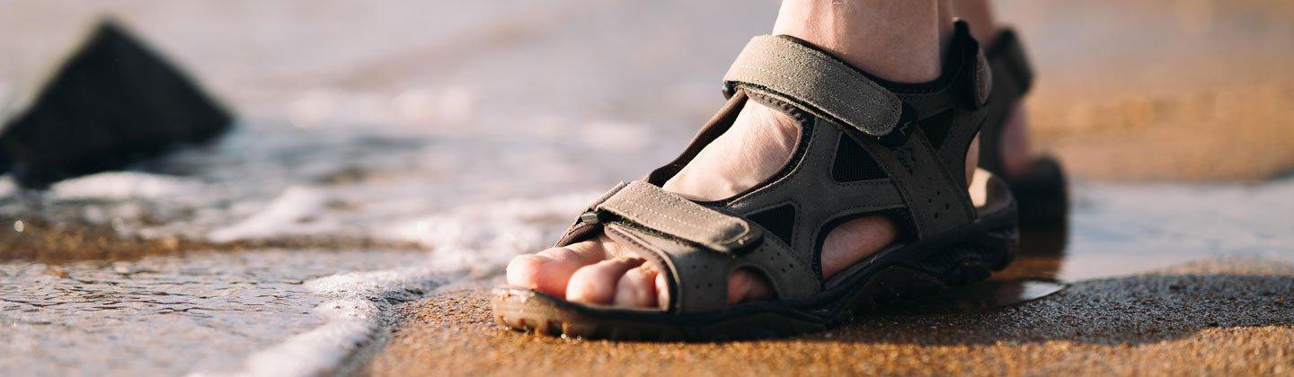 Closeup of a person walking on the beach in a pair of sandals