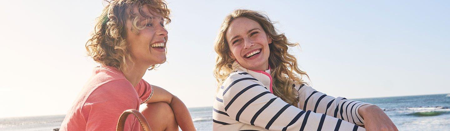 Two people smiling in the sun on the beach
