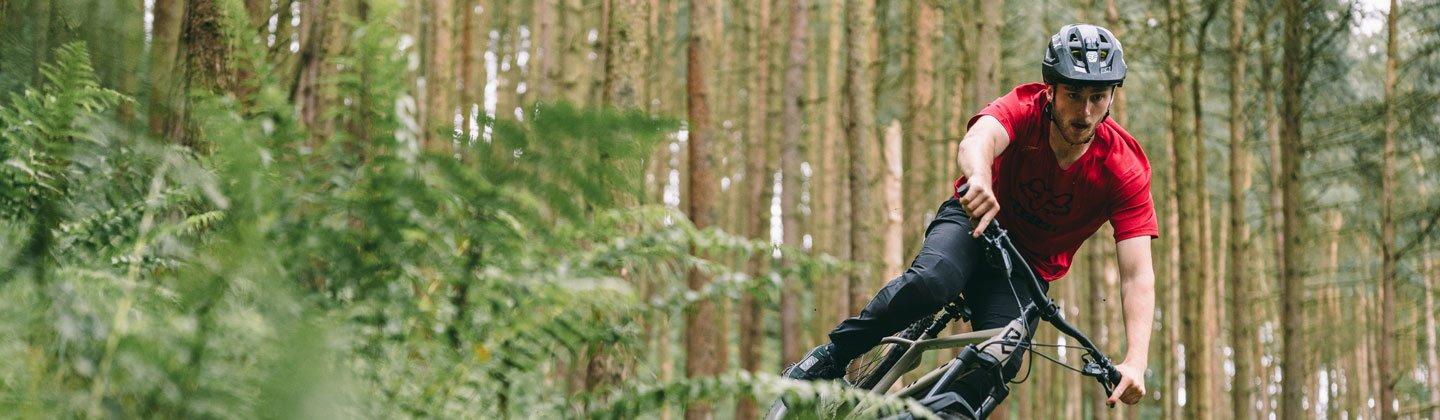 A person riding their mountain bike through a forest wearing a helmet