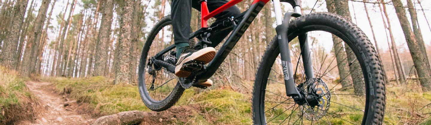 Closeup of a person in the air riding a mountain bike with the pedals in focus
