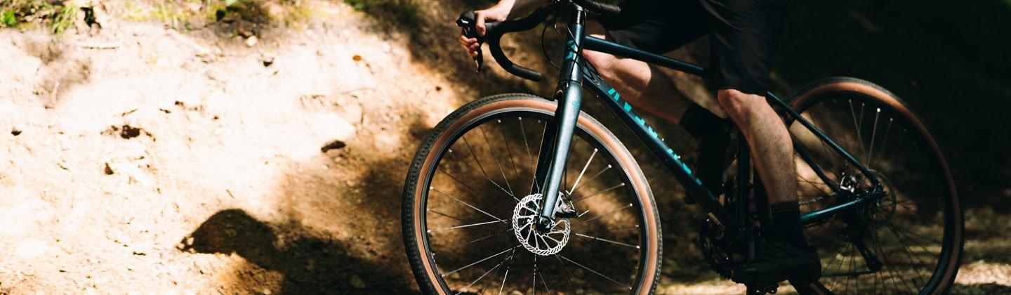 Closeup image of a person cycling through a forest with the camera focusing on the bike tyres