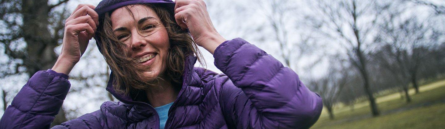 A person with their hood up wearing an insulated jacket and sheltering from the wind