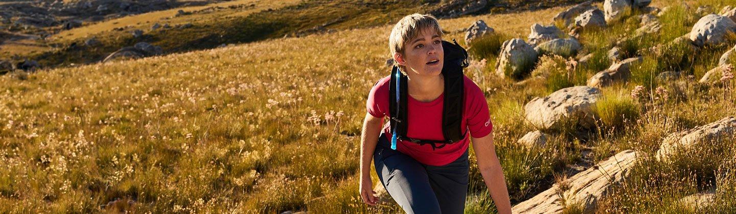 A person hiking in the hills wearing a hydration pack