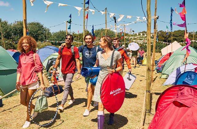 People walking through a festival carrying tents