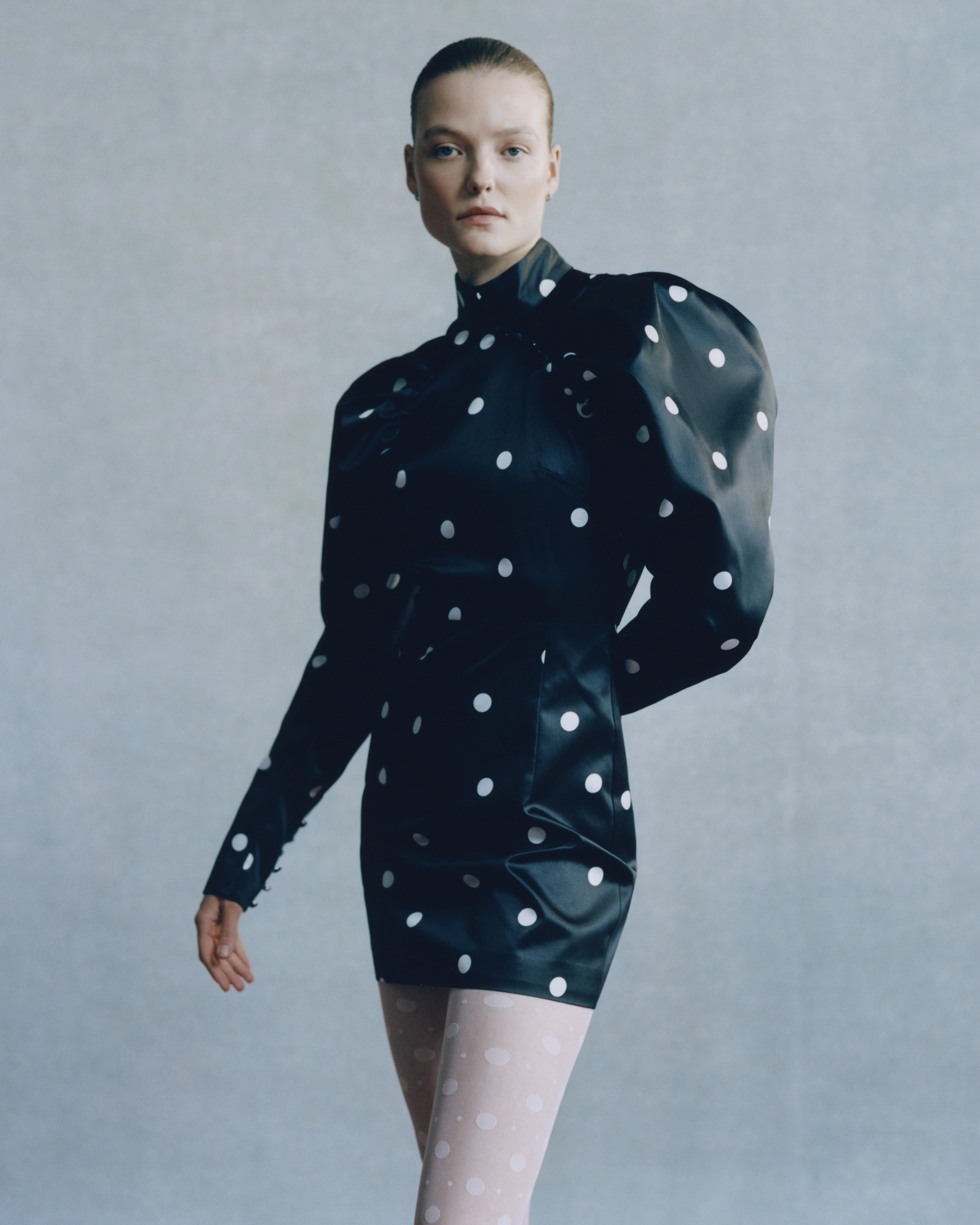 Woman wearing a ROTATE mini dress and white tights