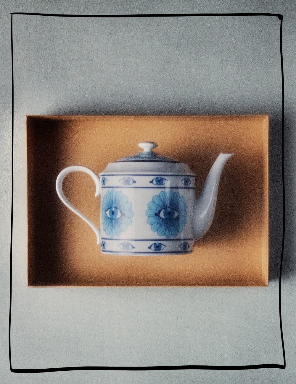 An ornate teapot in shades of blue appears in a curatorial box