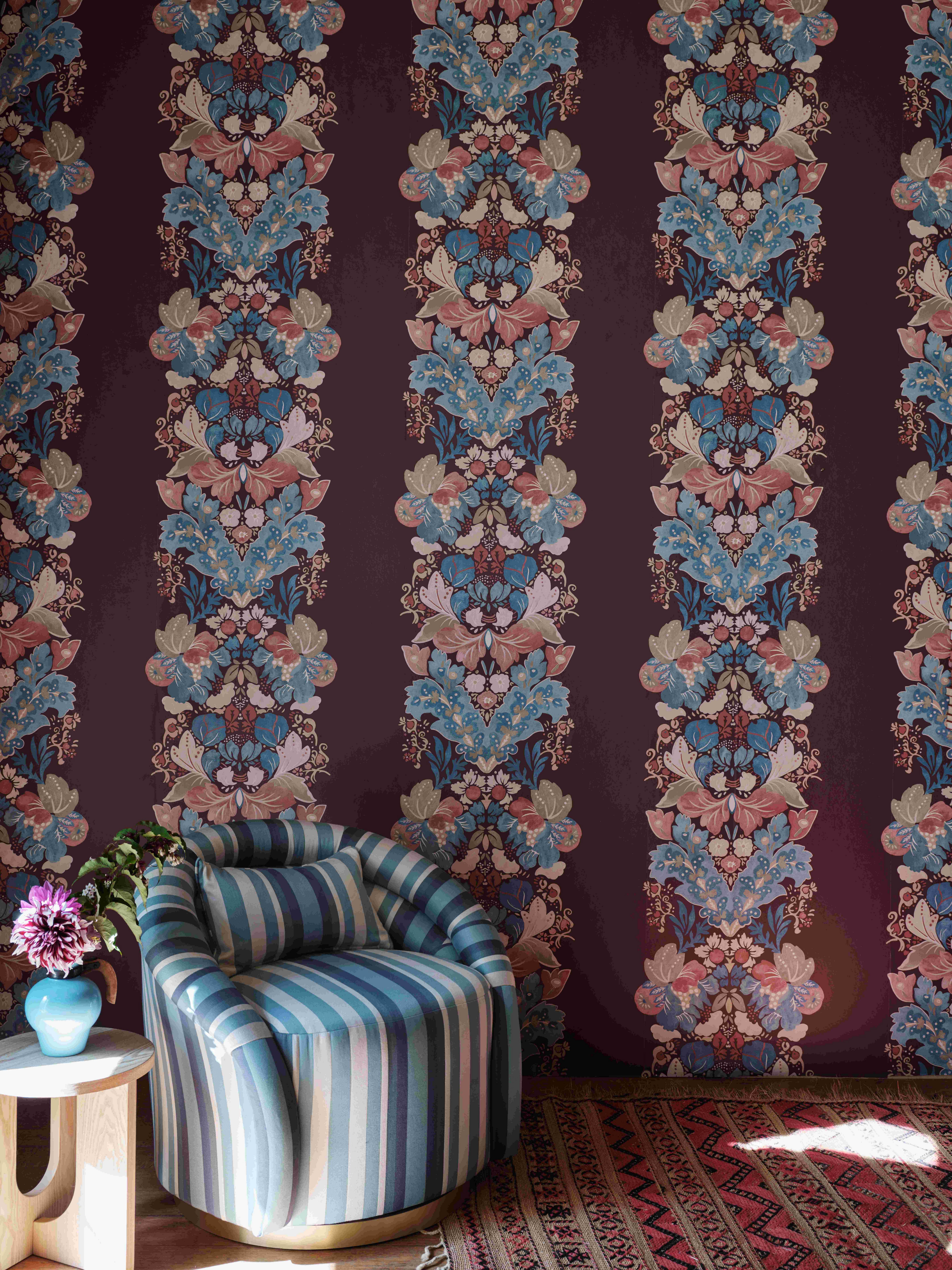 A striped armchair against a floral striped wall in burgundy and blue tones 