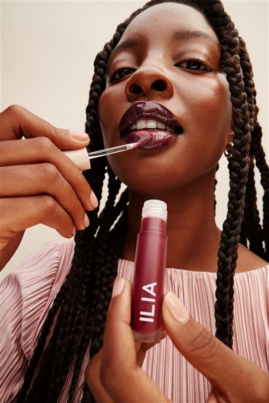 Model applies ILIA Beauty's Overglaze Hydrating Lip Gloss 5ml in the shade Resin