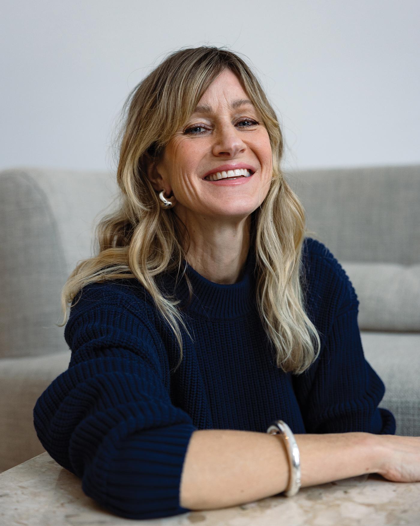 Jenny Bird sits wearing a black jumper and a selection of elegant jewellery