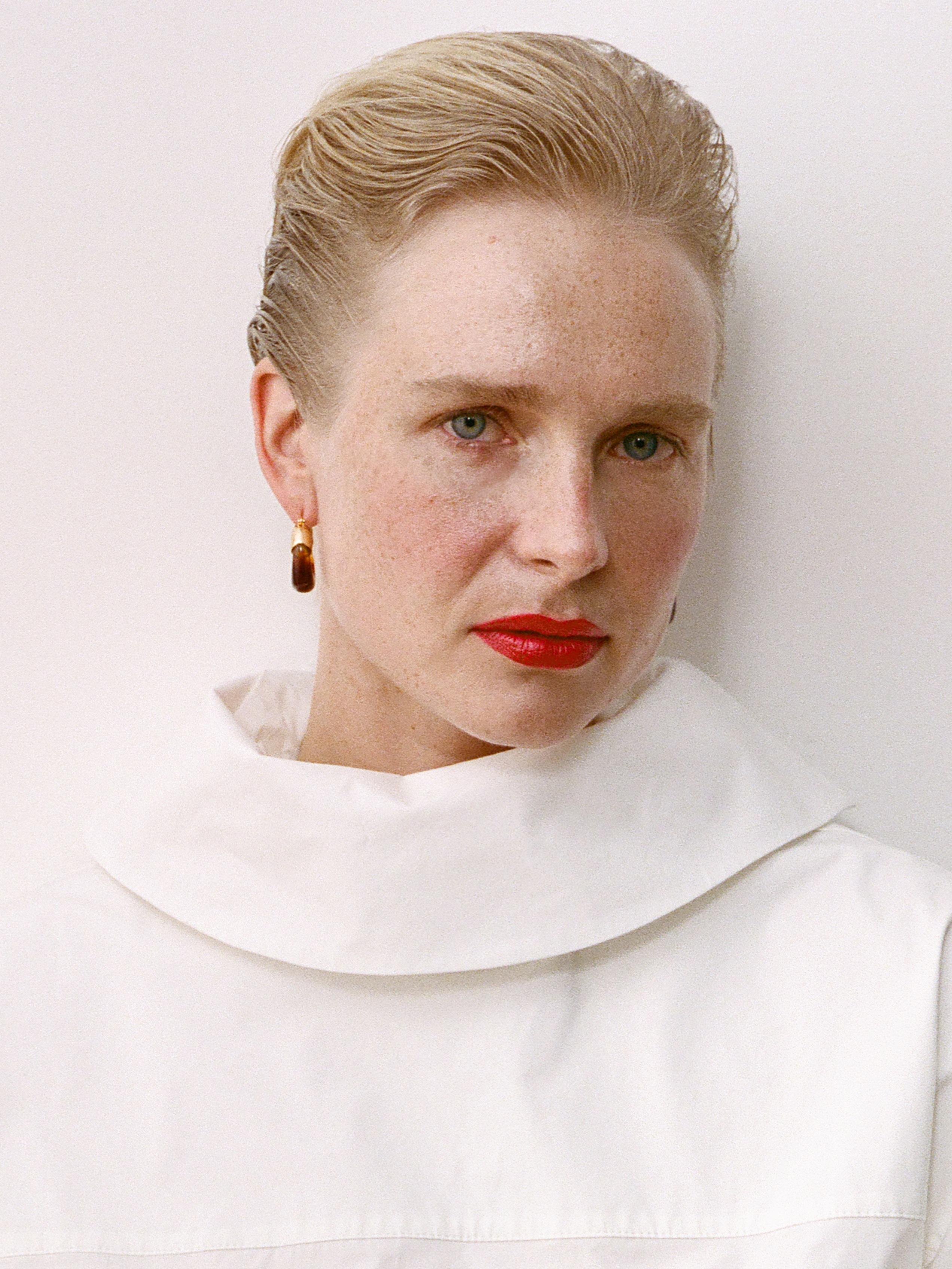 Model wearing bright red lipstick and a white high-necked blouse