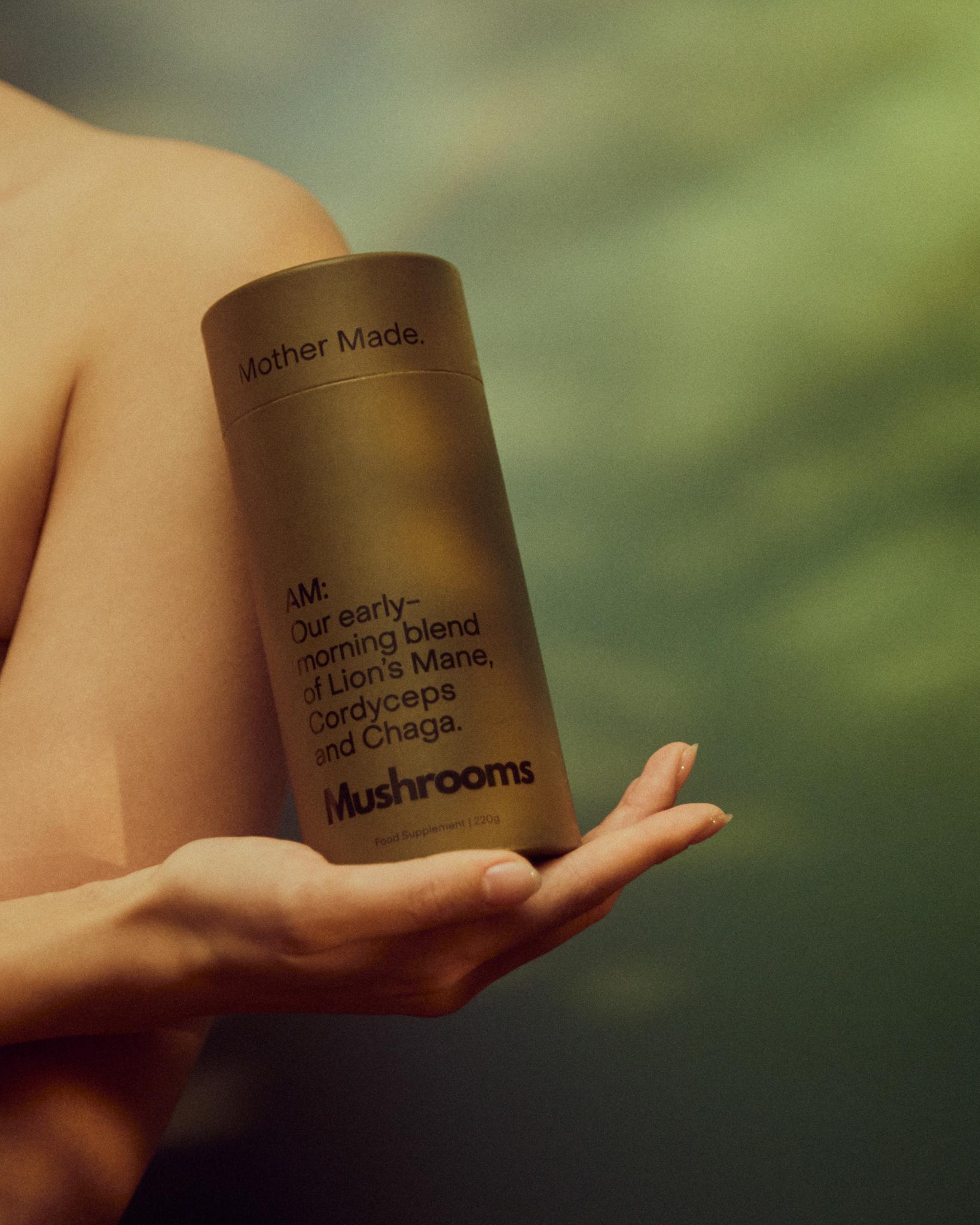 A hand holding a tub of mushroom supplements by Mother Made