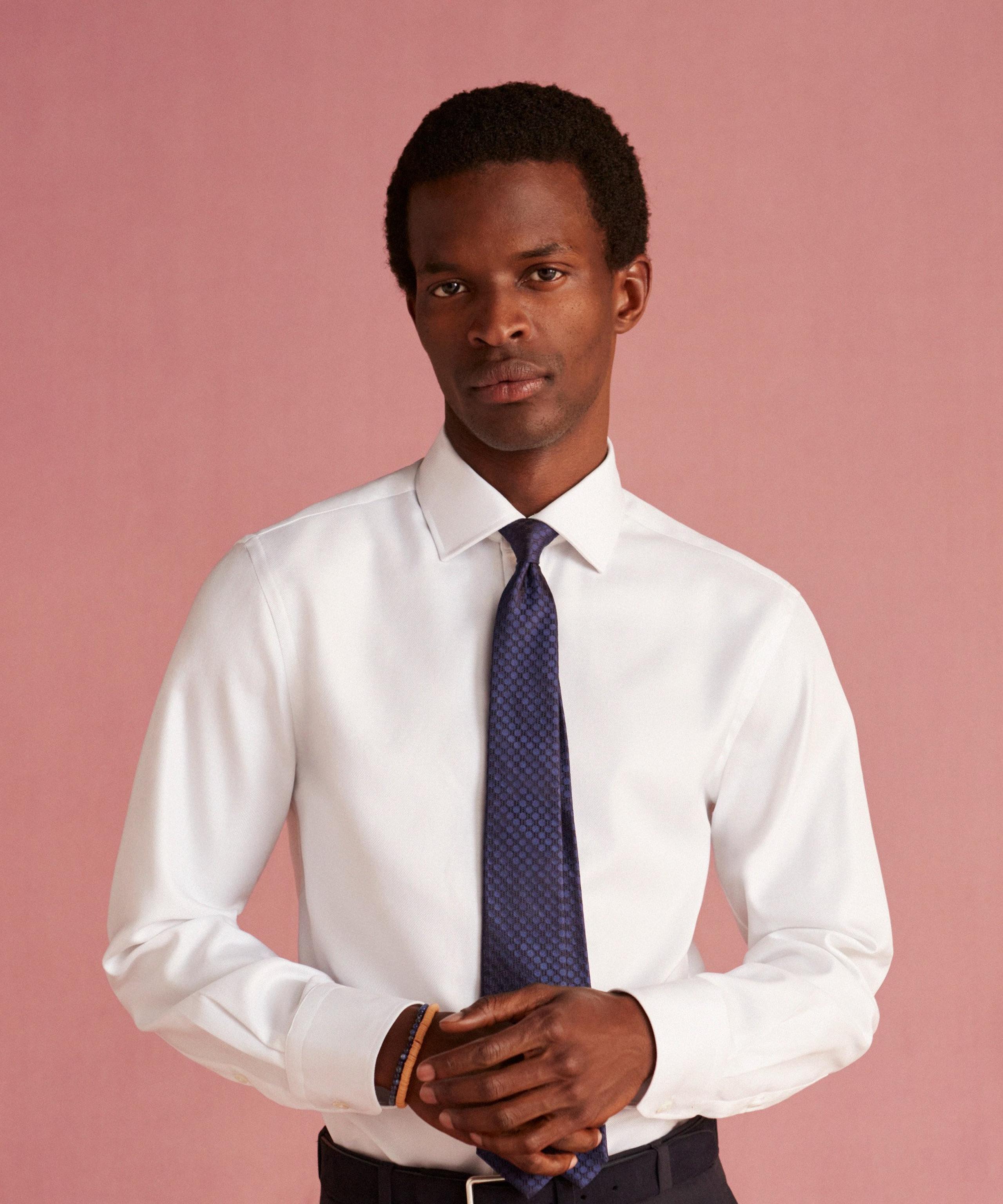 A man wears a white shirt with navy tie