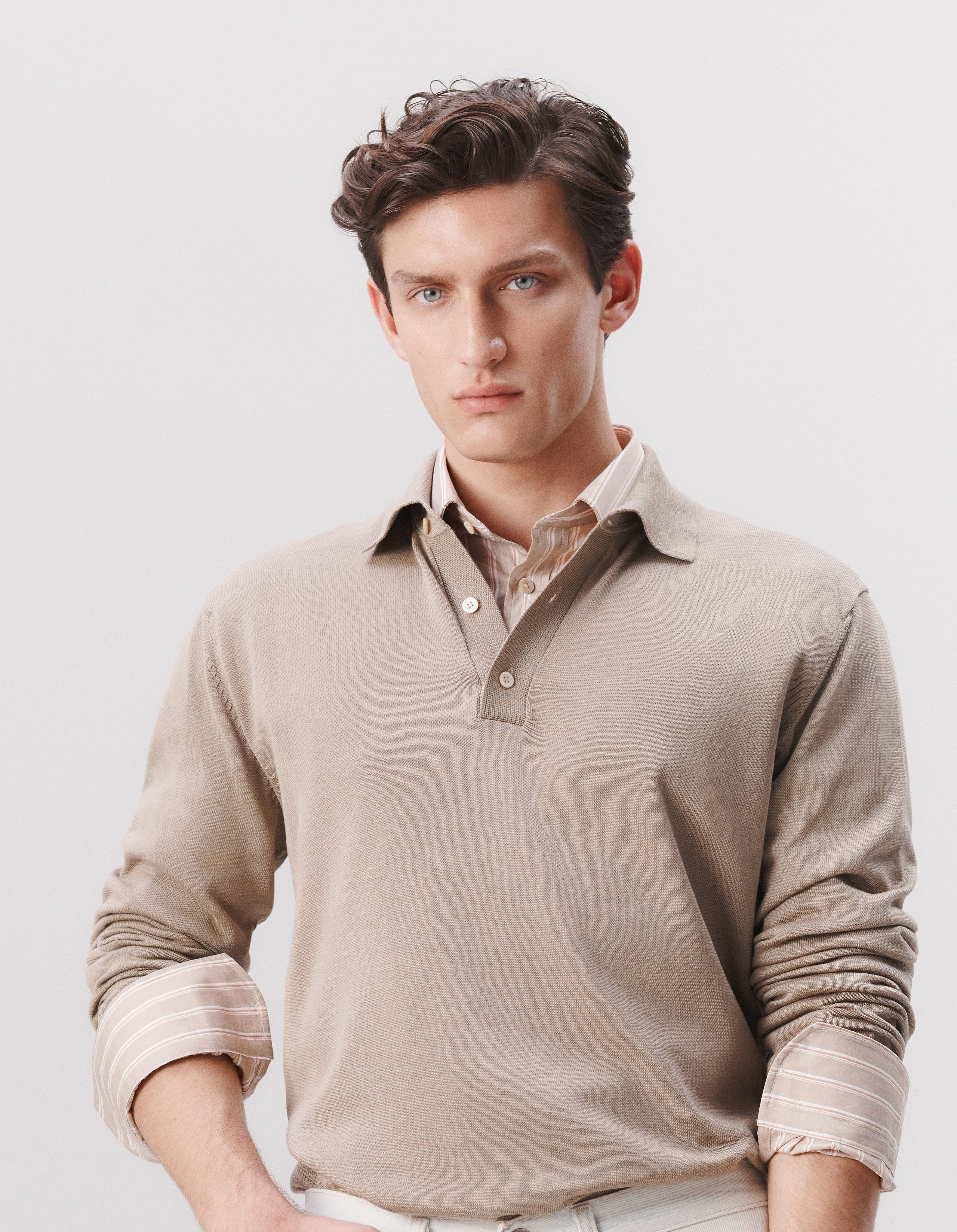 A man wears a shirt layered with a long sleeve polo shirt on top