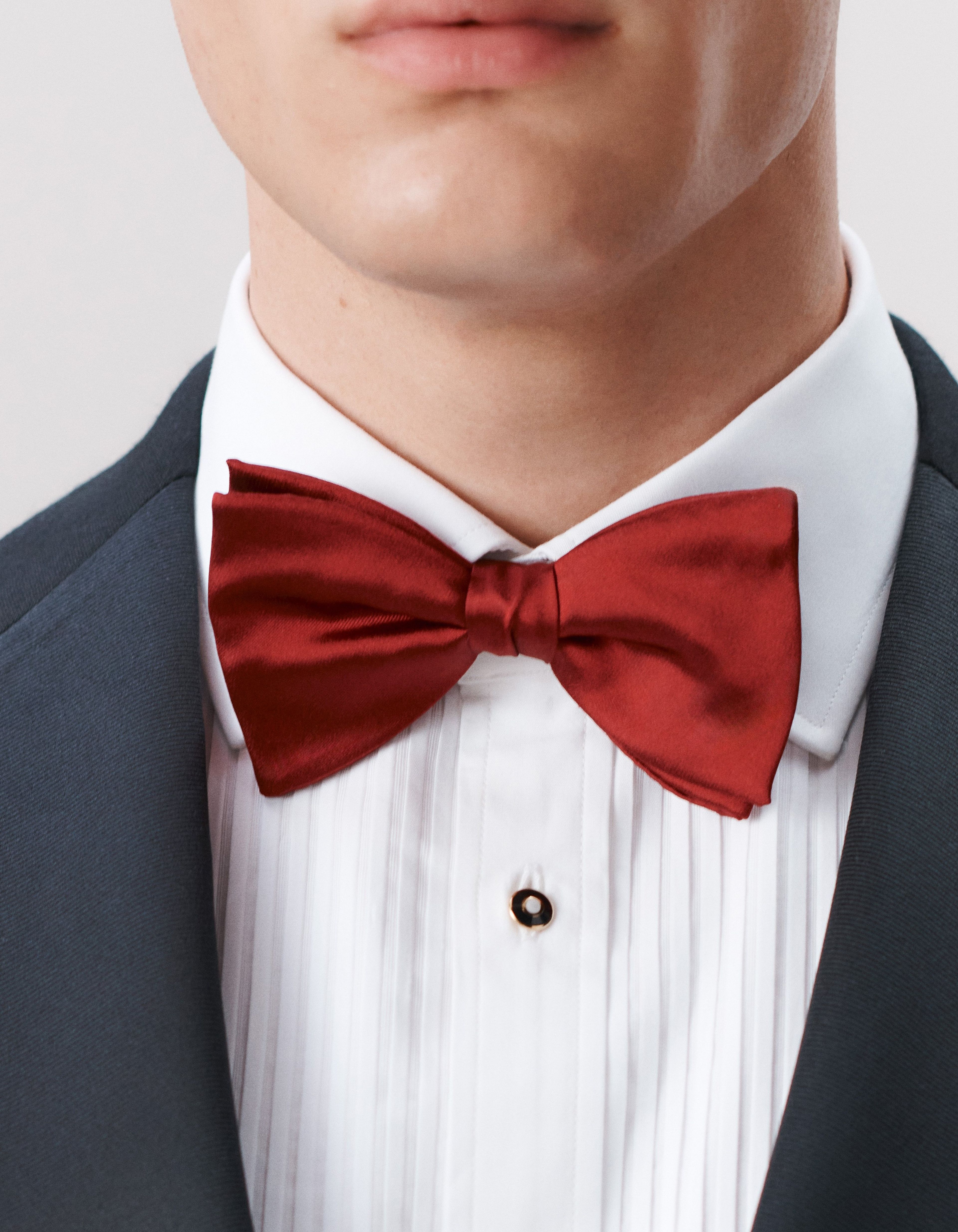 A close up of a man wearing a black evening jacket, white evening shirt with a red bow tie