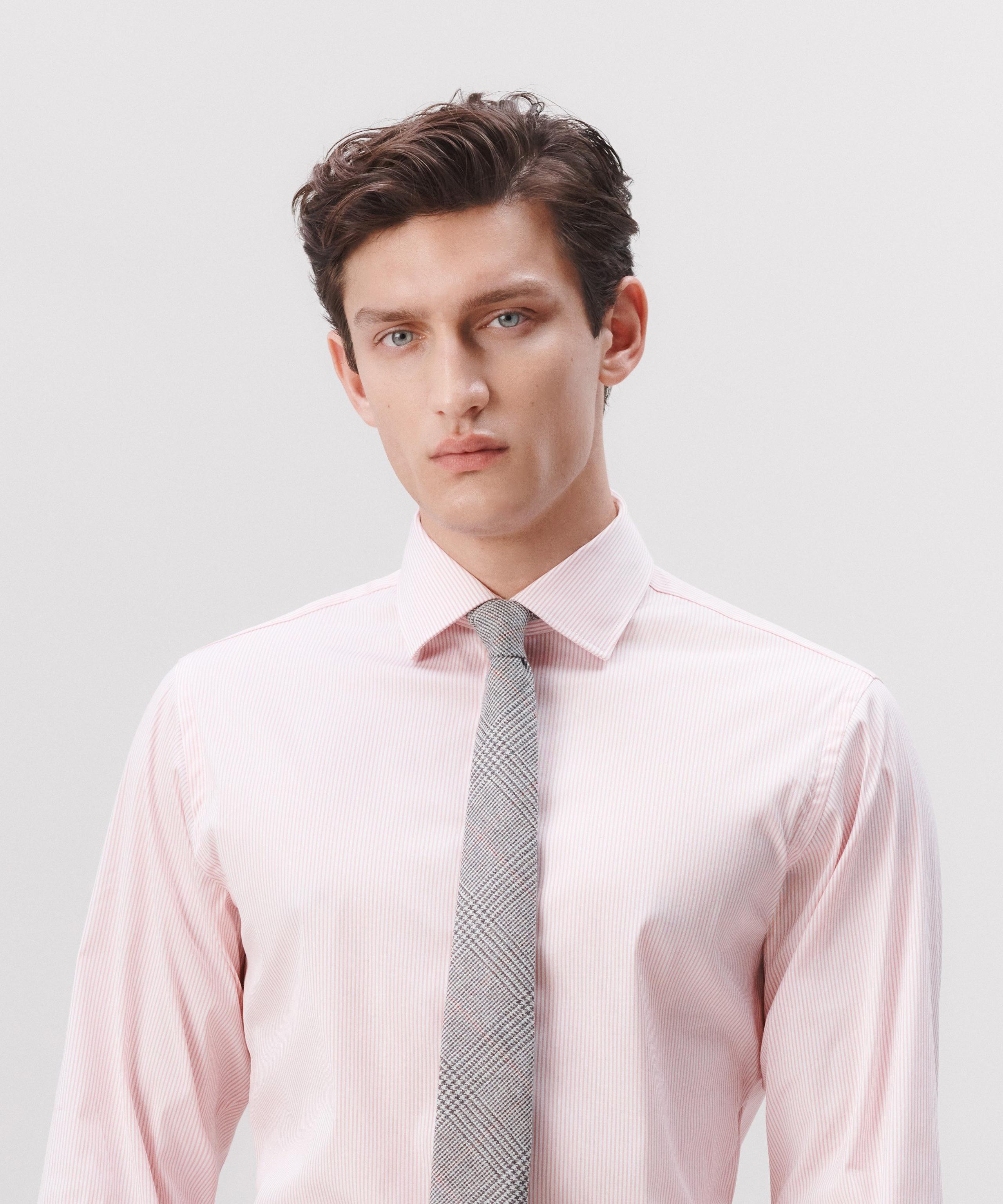 A man wearing a pink striped shirt with a grey tie