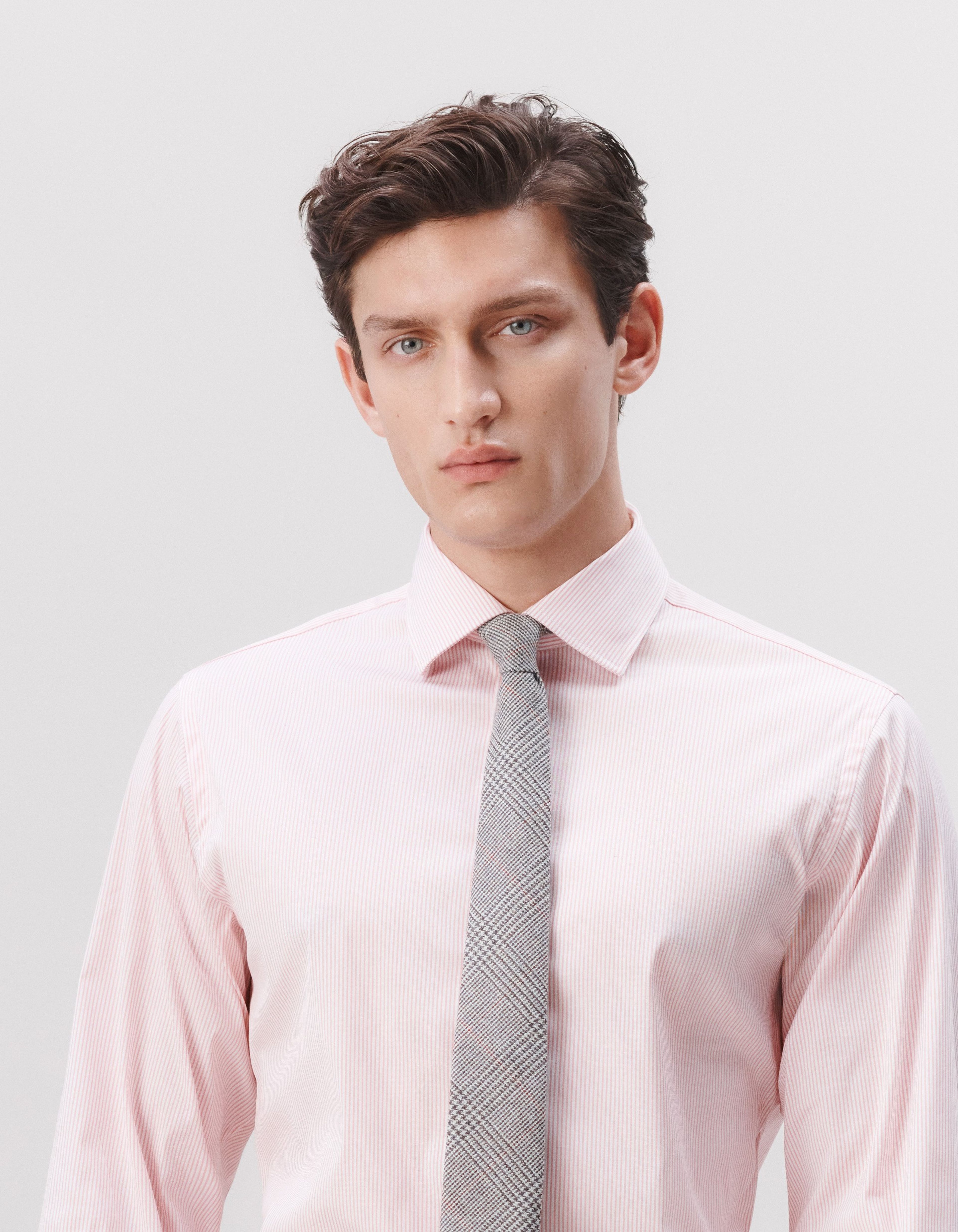 A man wearing a pink striped shirt with a grey tie