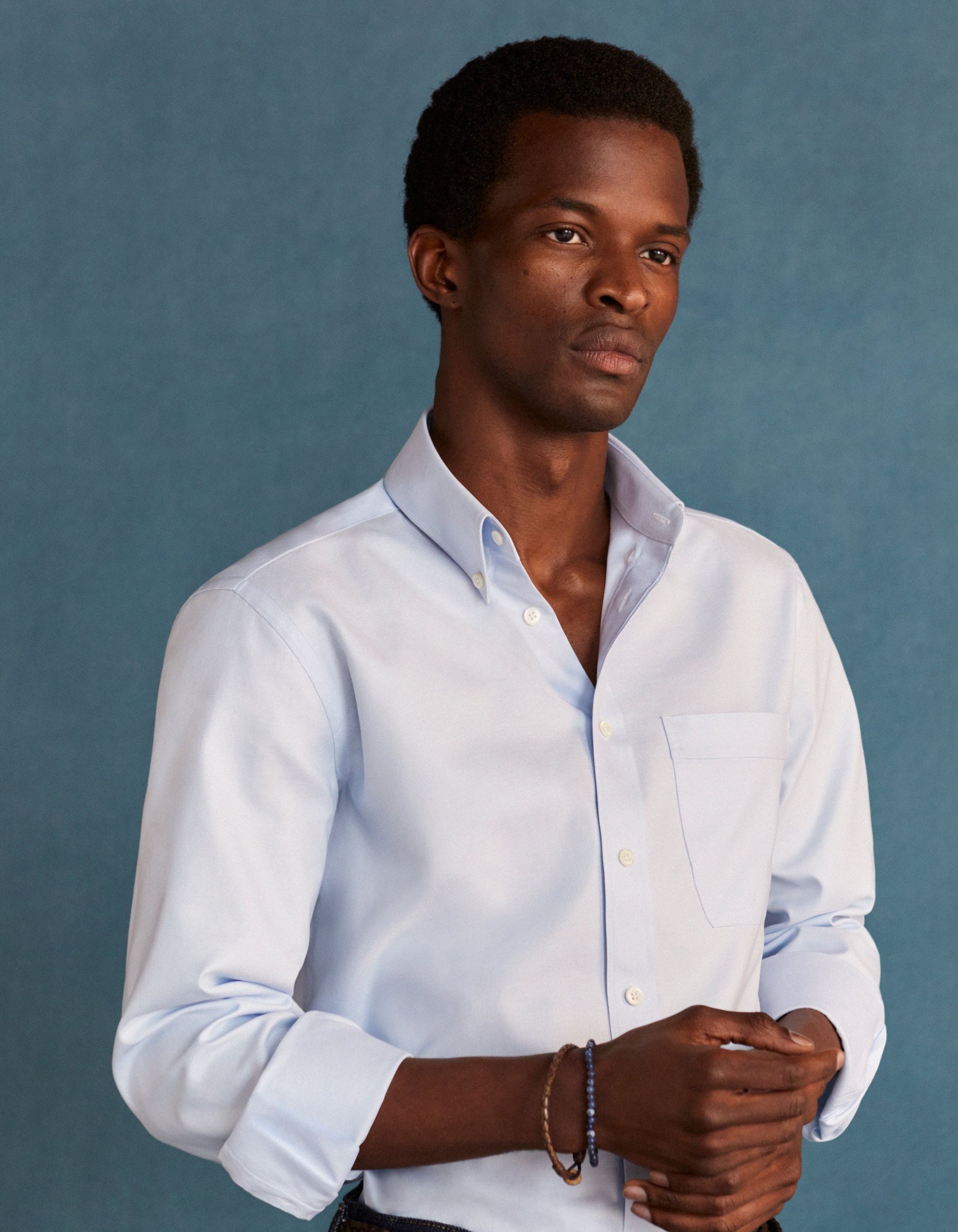 A man wears a blue button down collar shirt