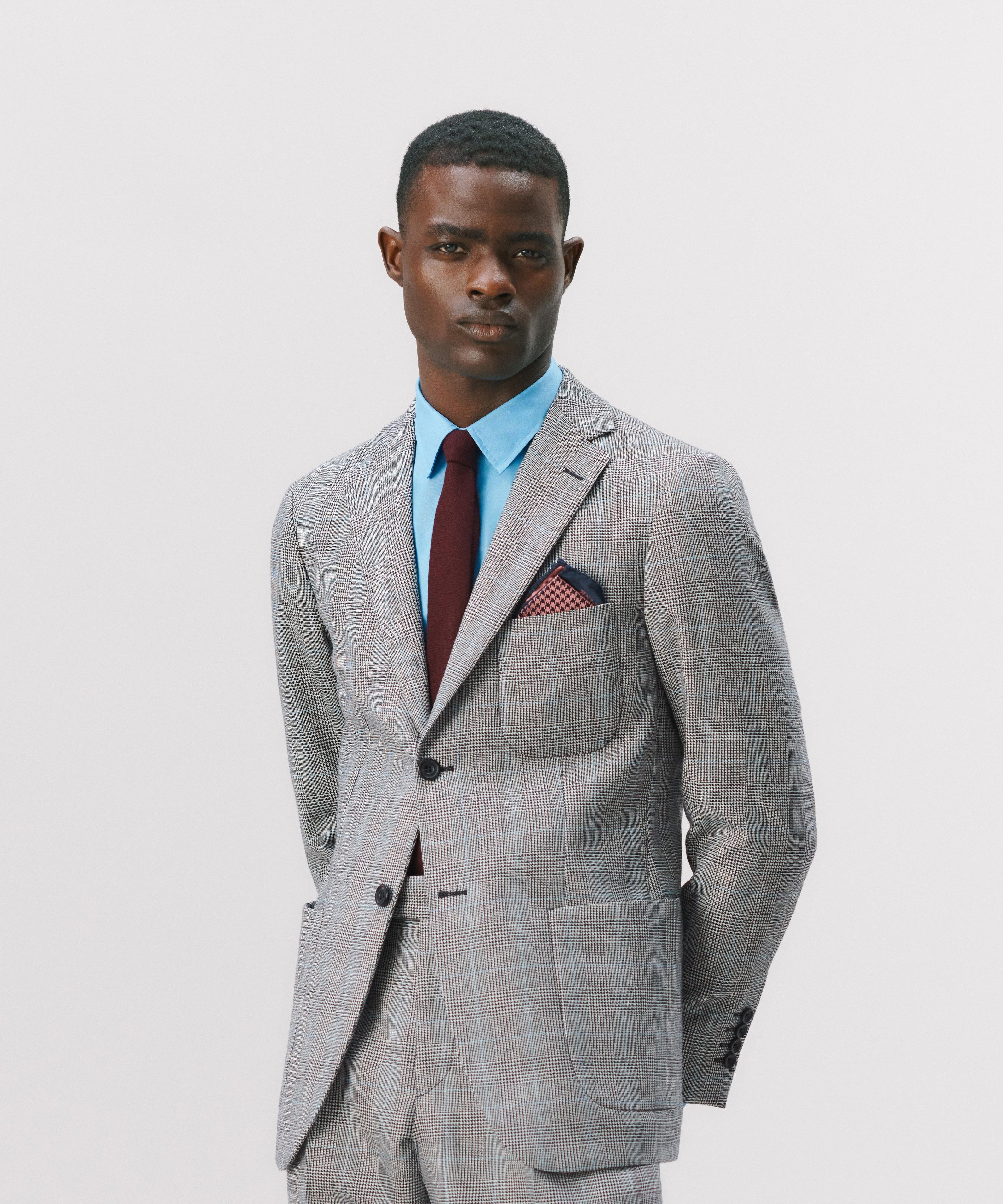 A man wearing a grey suit with a blue shirt and red tie