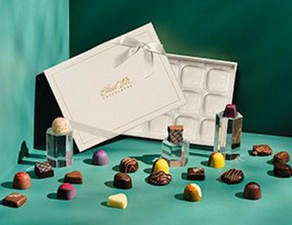 Cream Custom Chocolate Box with scattered gems on a blue/green background