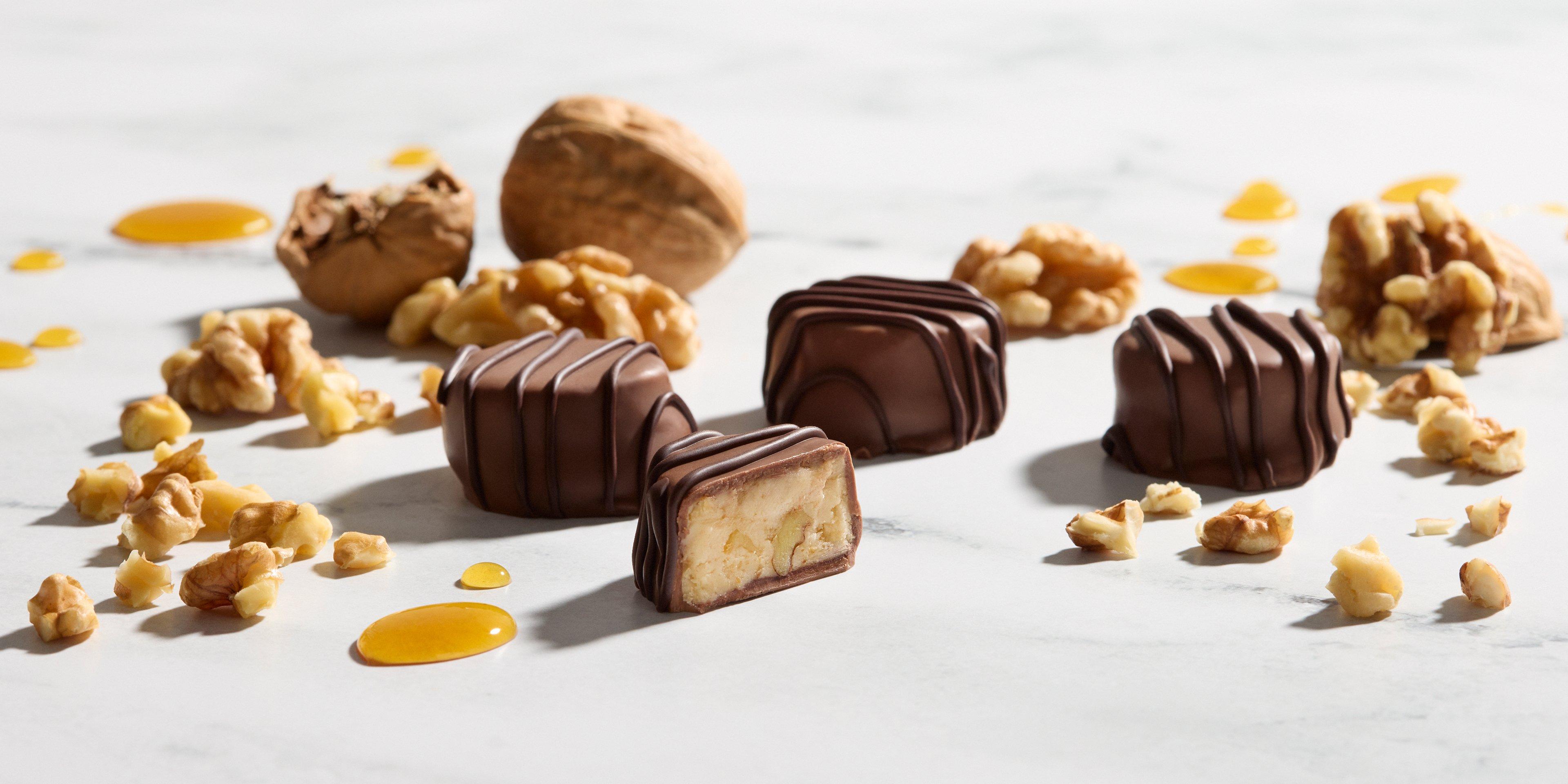 Maple Walnut Satin Crème Milk Chocolate opened on marble background with crushed walnuts
