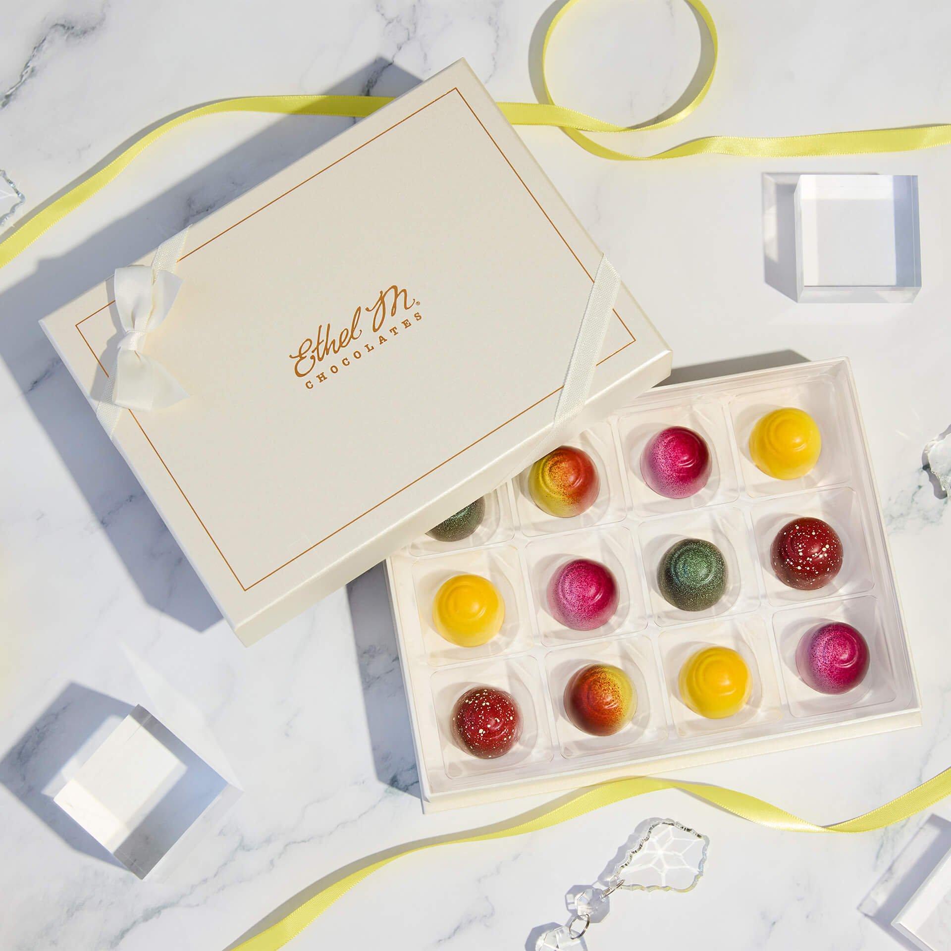 Cream Custom Chocolate Box with Fruit Fusion truffles on a marble background with yellow ribbon