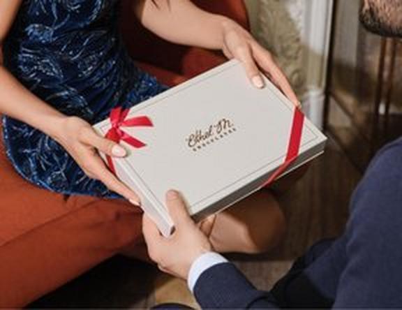 One Person Handing Another an Ethel M Chocolates Custom Chocolate Box