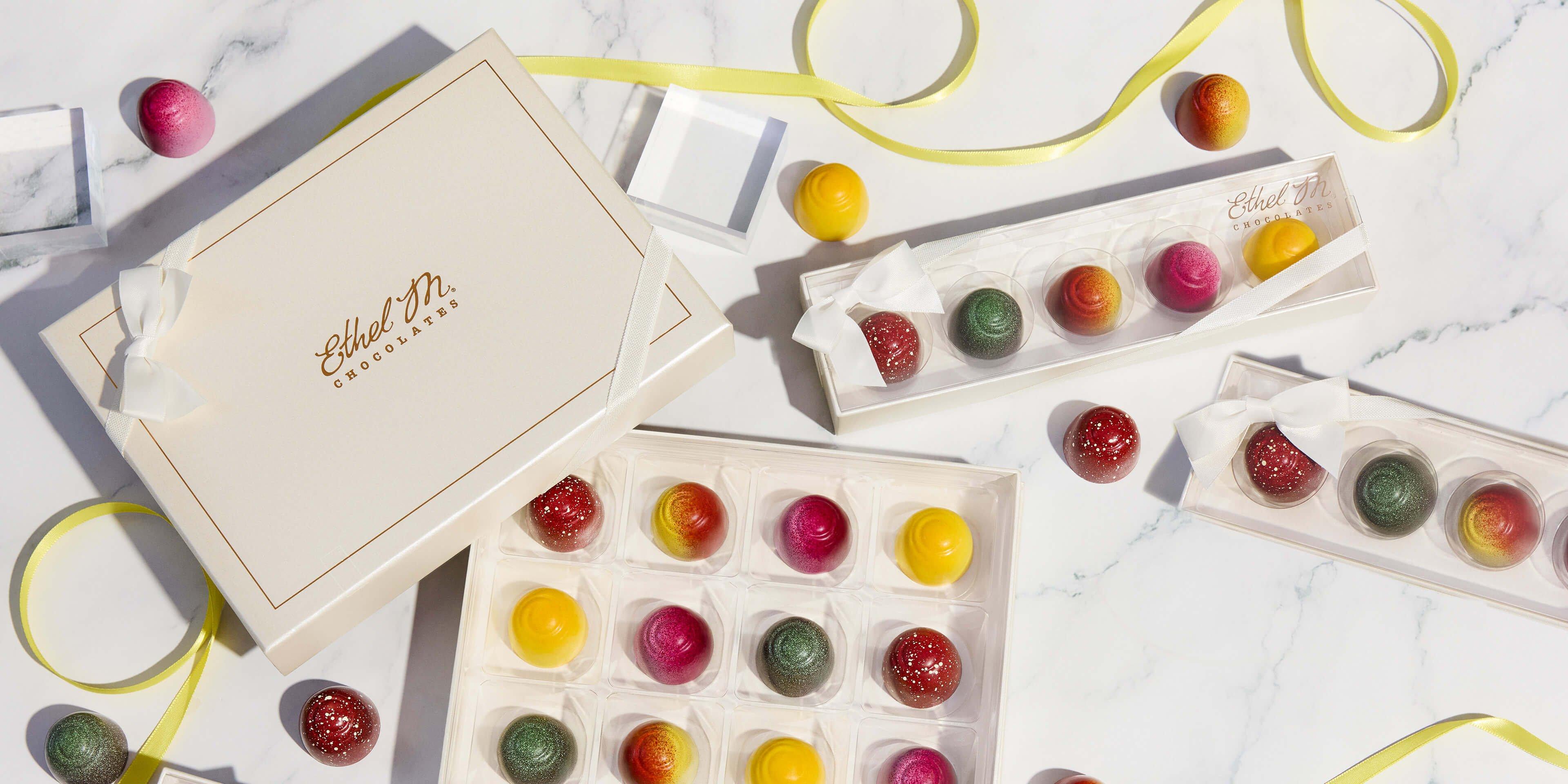 Fruit Fusion Sampler & 12 piece Fruit Fusion Custom Chocolate Box in cream packaging on marble background with yellow ribbon