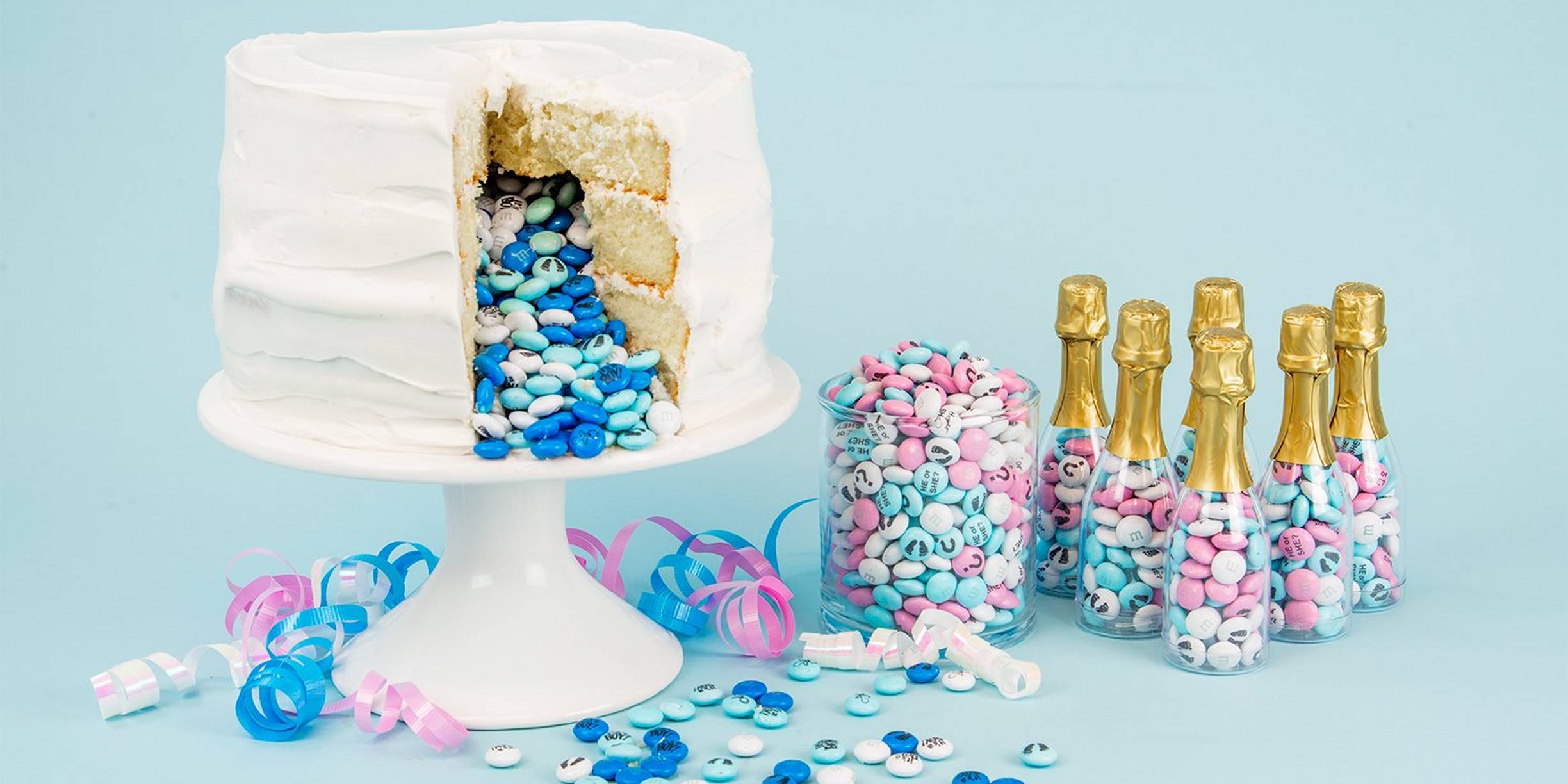 baby boy gender reveal cake with blue and white personalized M&M'S spilling out