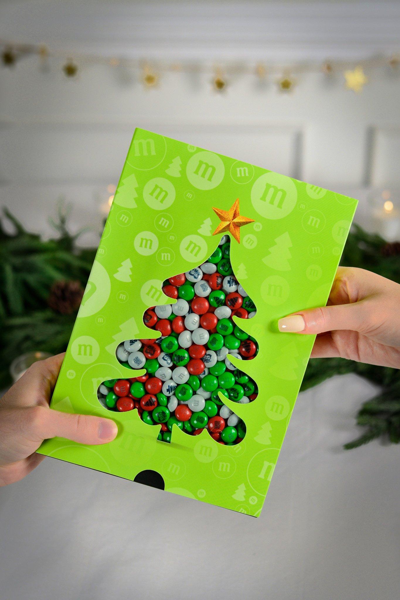 Een persoon die een M&M'S-doos aanbiedt