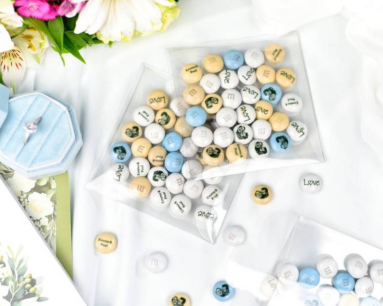 detalles en forma de corazón con M&M'S rojos y blancos repartiéndose en una boda