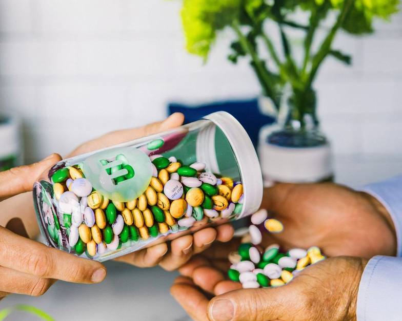 gift jar filled with St. Patrick's Day themed M&M'S being poured into another person's hand