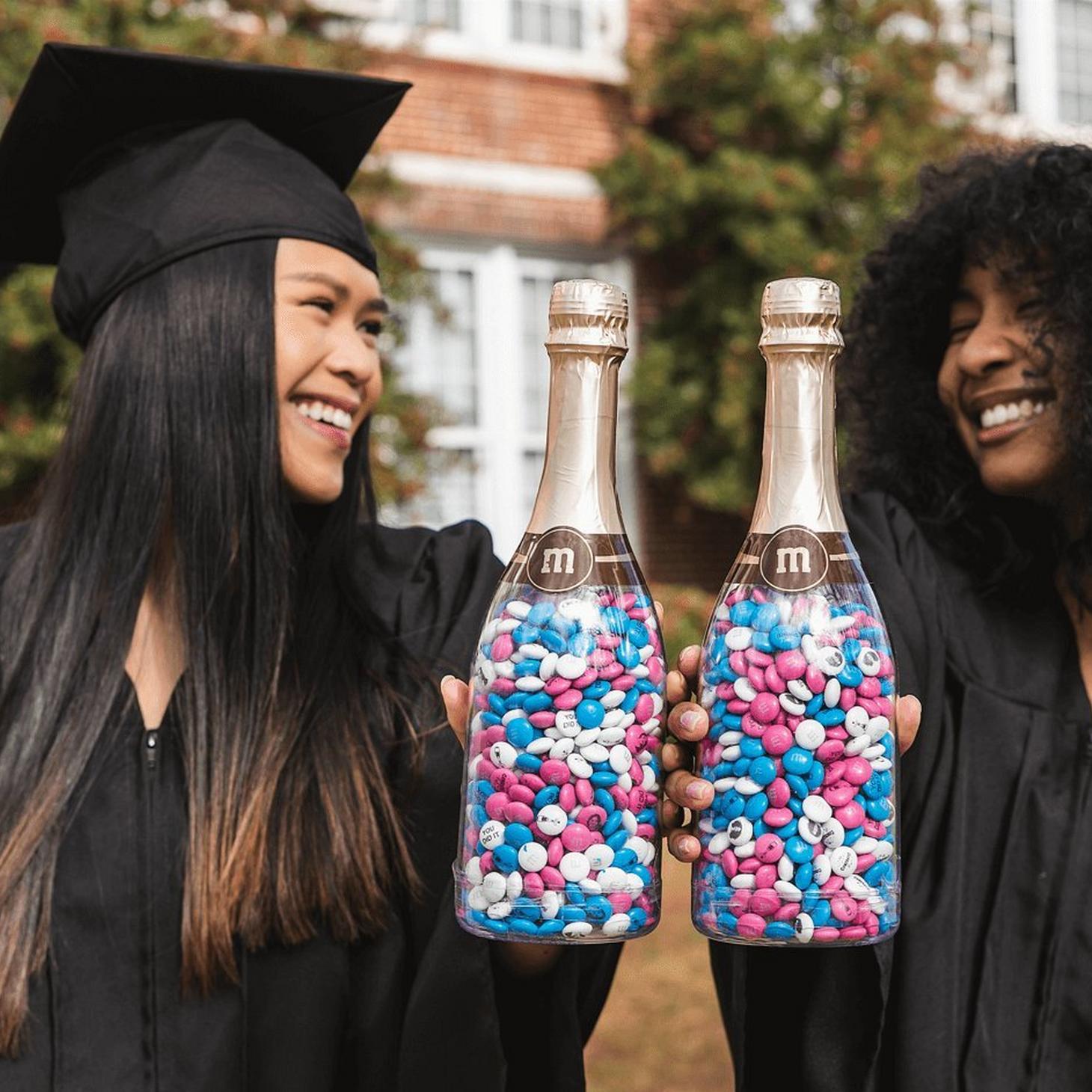 two graduates holding occasion bottles