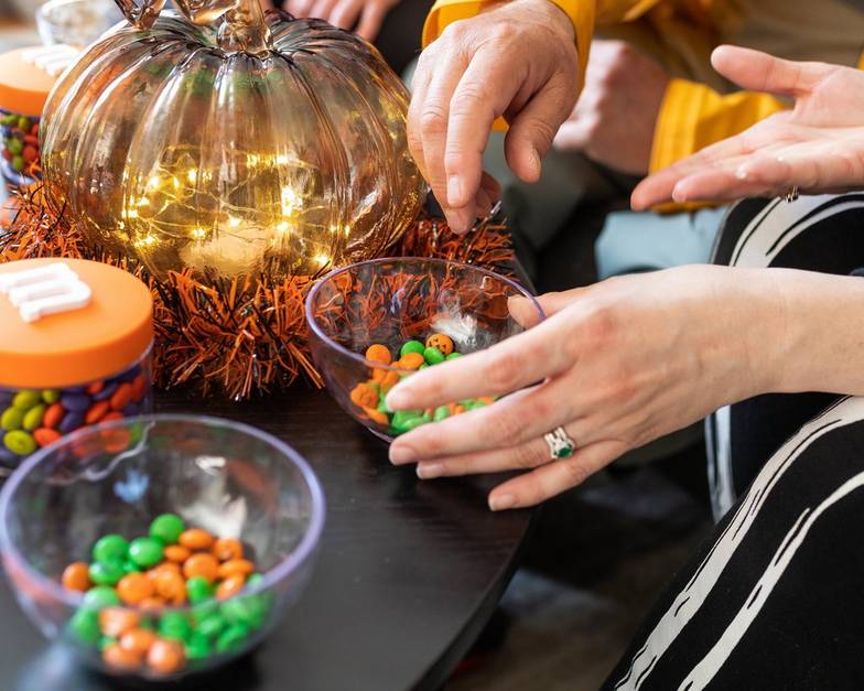 bowl of personalized M&M'S on table and people reaching for some