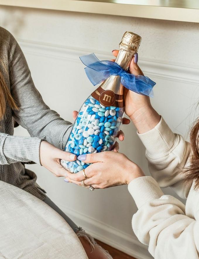 two best friends gifting one another Hanukkah themed M&M'S in a gift bottle