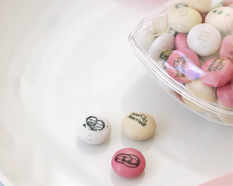 heart-shaped party favors filled with red and white M&M'S being handed out at a wedding