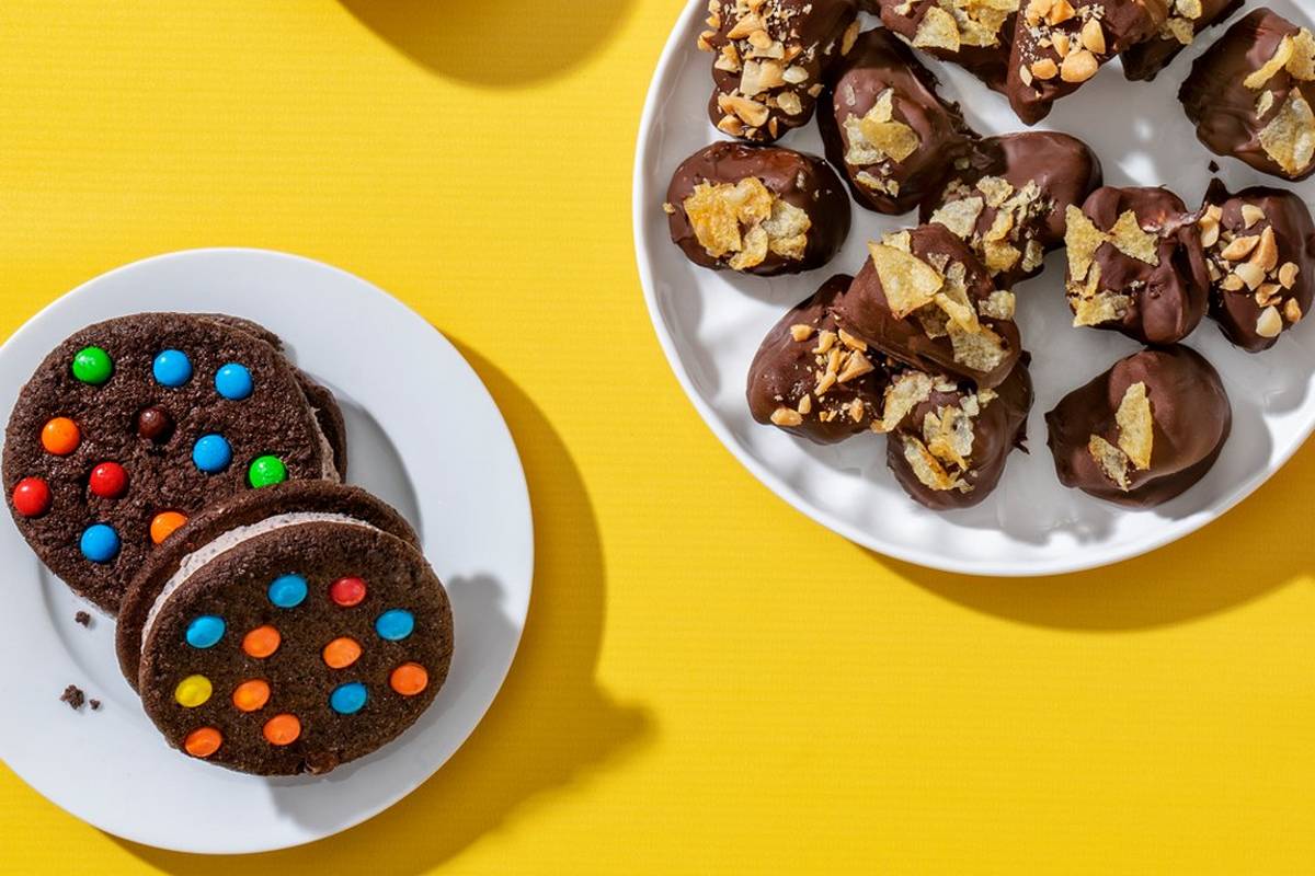 Plate of frozen bonbons along with a plate of 2 ice cream sandwiches.