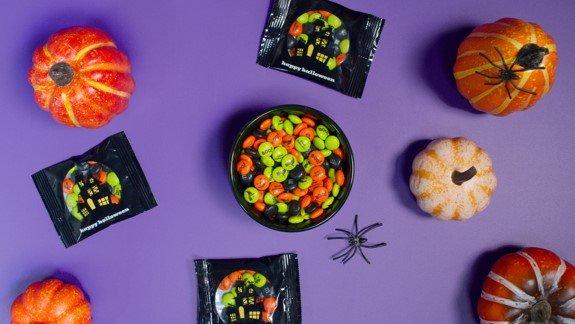 bowl of personalized M&M'S and party favors on table and people reaching for some