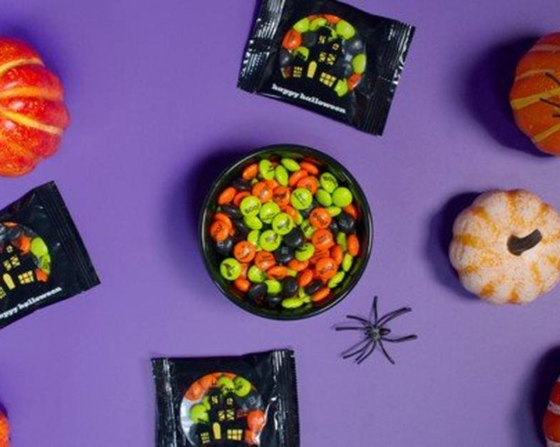 bowl of personalized M&M'S and party favors on table and people reaching for some