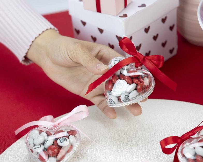 rote und weiße M&M'S in einem durchsichtigen Herz mit roter Schleife