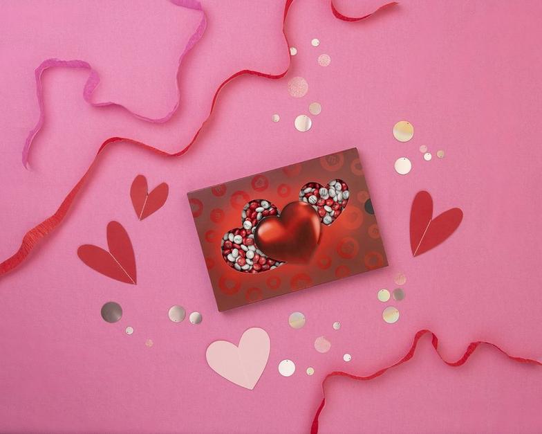 rote Box, verziert mit Herzen und im Inneren rote, weiße und rosa M&M’S