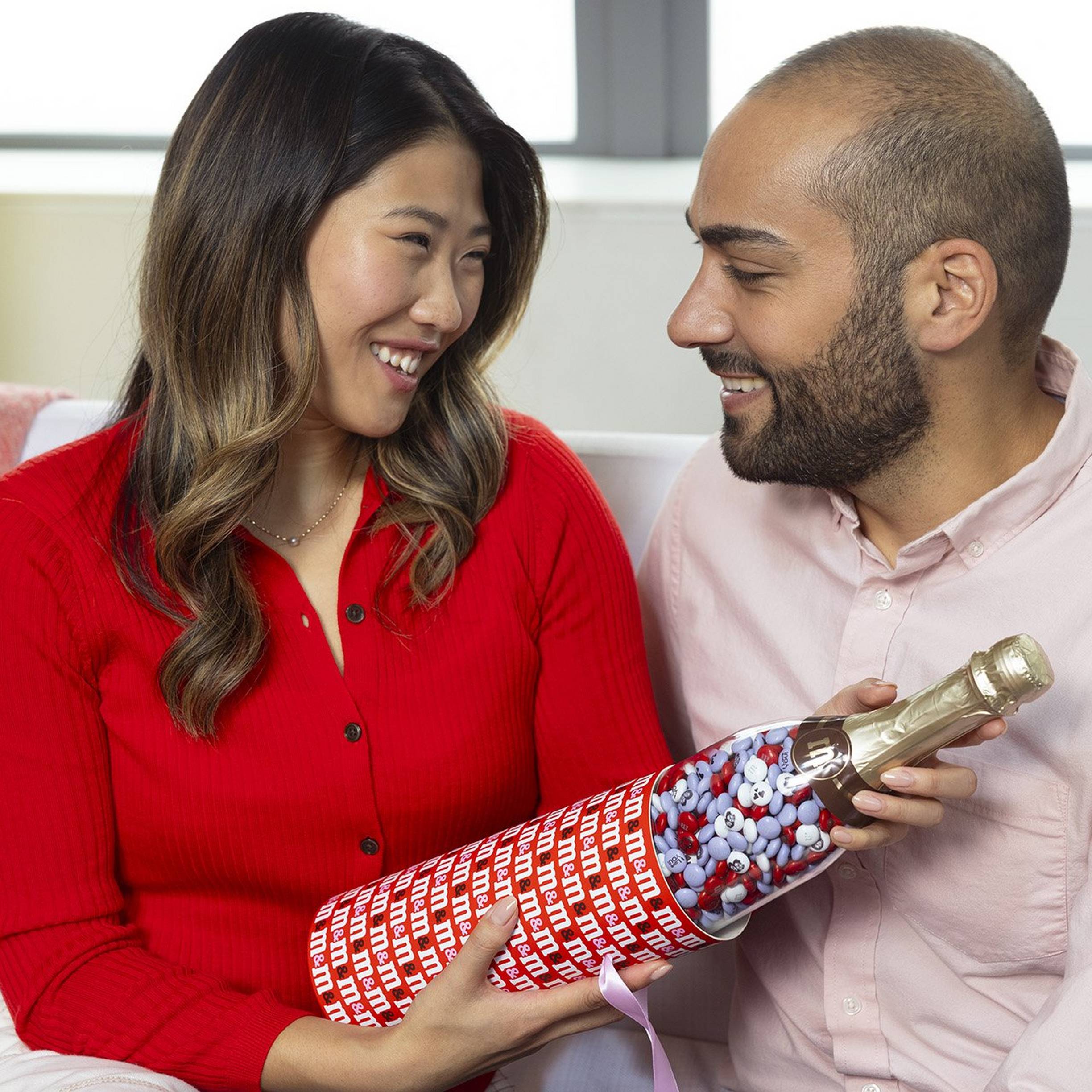 family of four on the couch laughing and enjoying gifting one another for Valentine's Day
