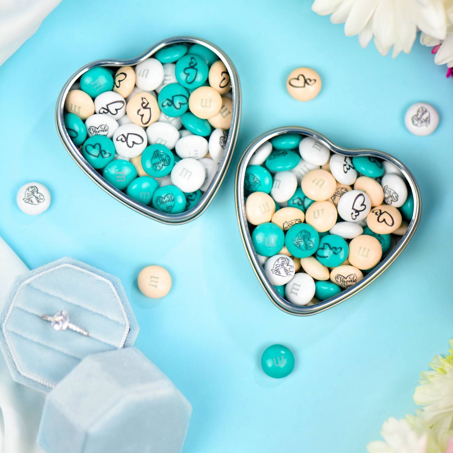 heart favor tins showing personalized M&M'S surrounded by wedding props