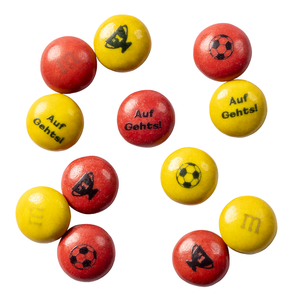 Dulces de chocolate M&M'S rojos y amarillos con impresiones de balones de fútbol, trofeos y el texto Auf Gehts!