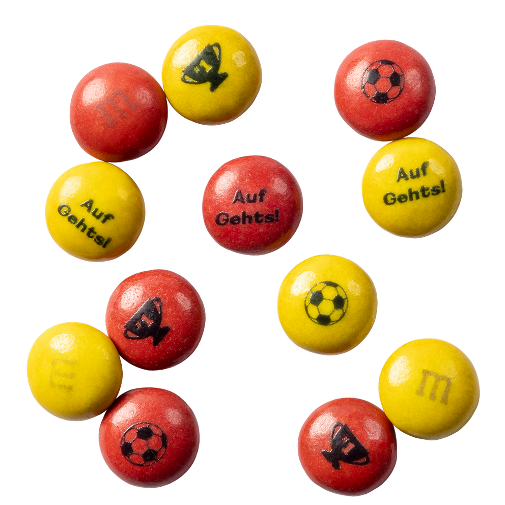 Dulces de chocolate M&M'S rojos y amarillos con impresiones de balones de fútbol, trofeos y el texto Auf Gehts!