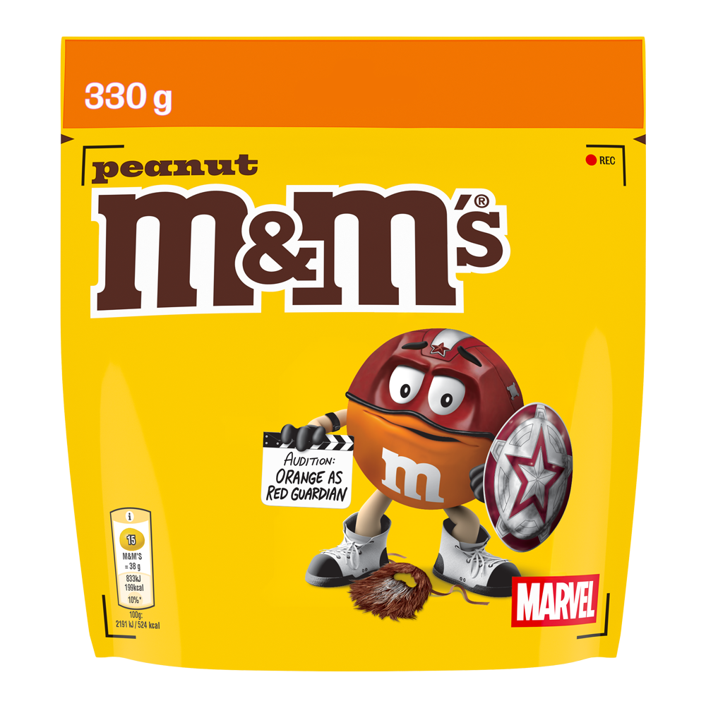 Bolsa de M&M'S peanut de 330g con Orange disfrazado de Red Guardian de MARVEL, sosteniendo un escudo y con una claqueta que dice "AUDITION: ORANGE AS RED GUARDIAN".