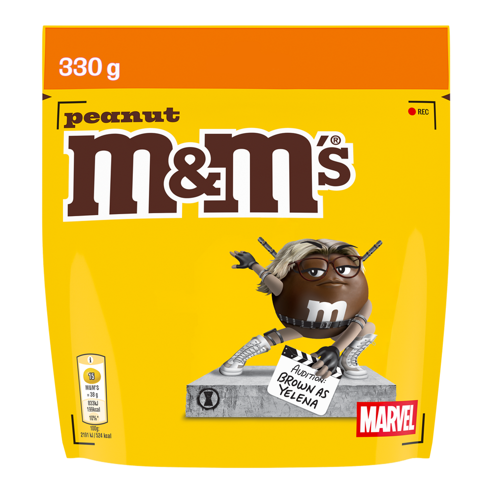 Zak M&M'S peanut snoepjes, 330g, met Brown als Yelena in auditie-outfit met klapbord.