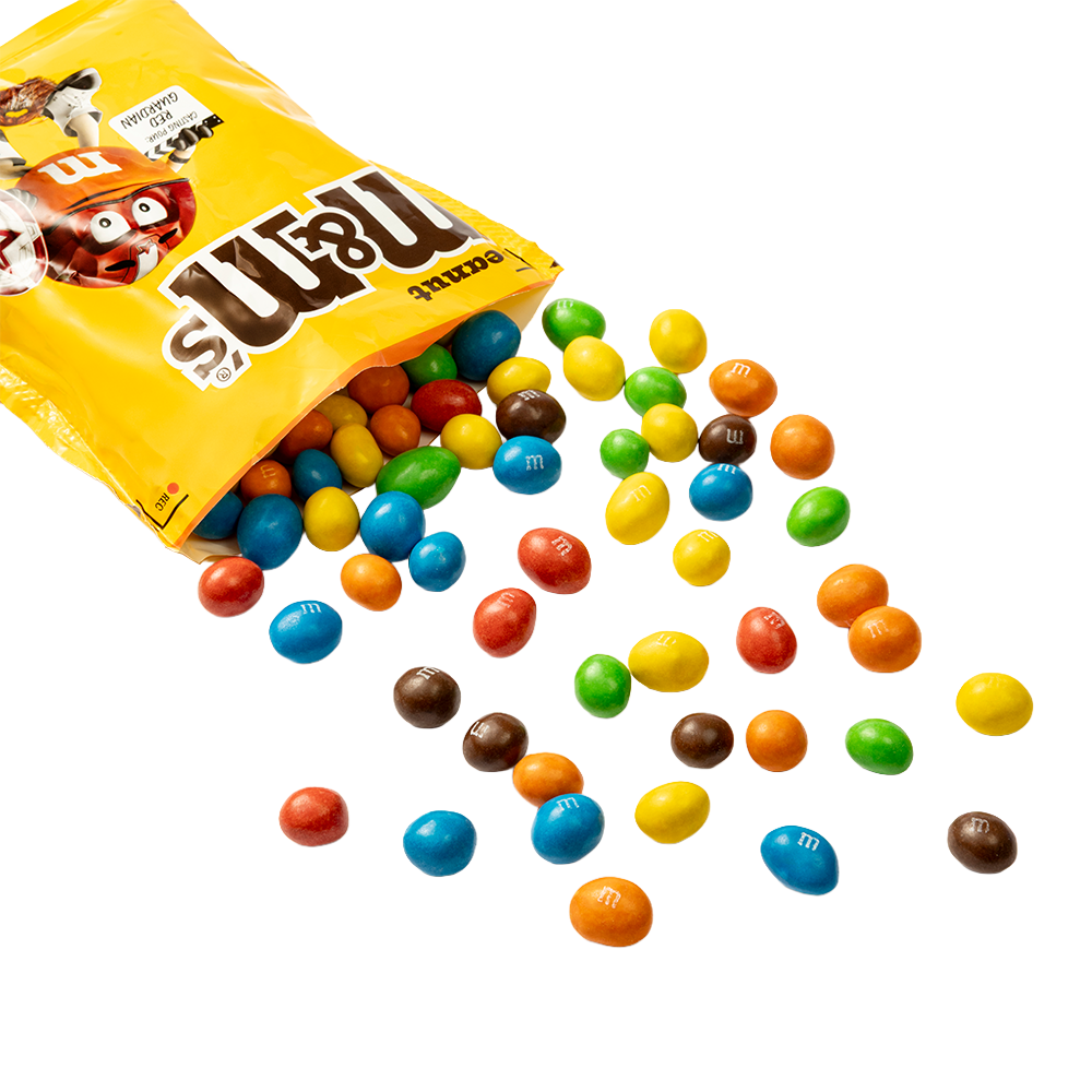 Bolsa amarilla de M&M'S con dulces de chocolate de colores derramados sobre fondo blanco.