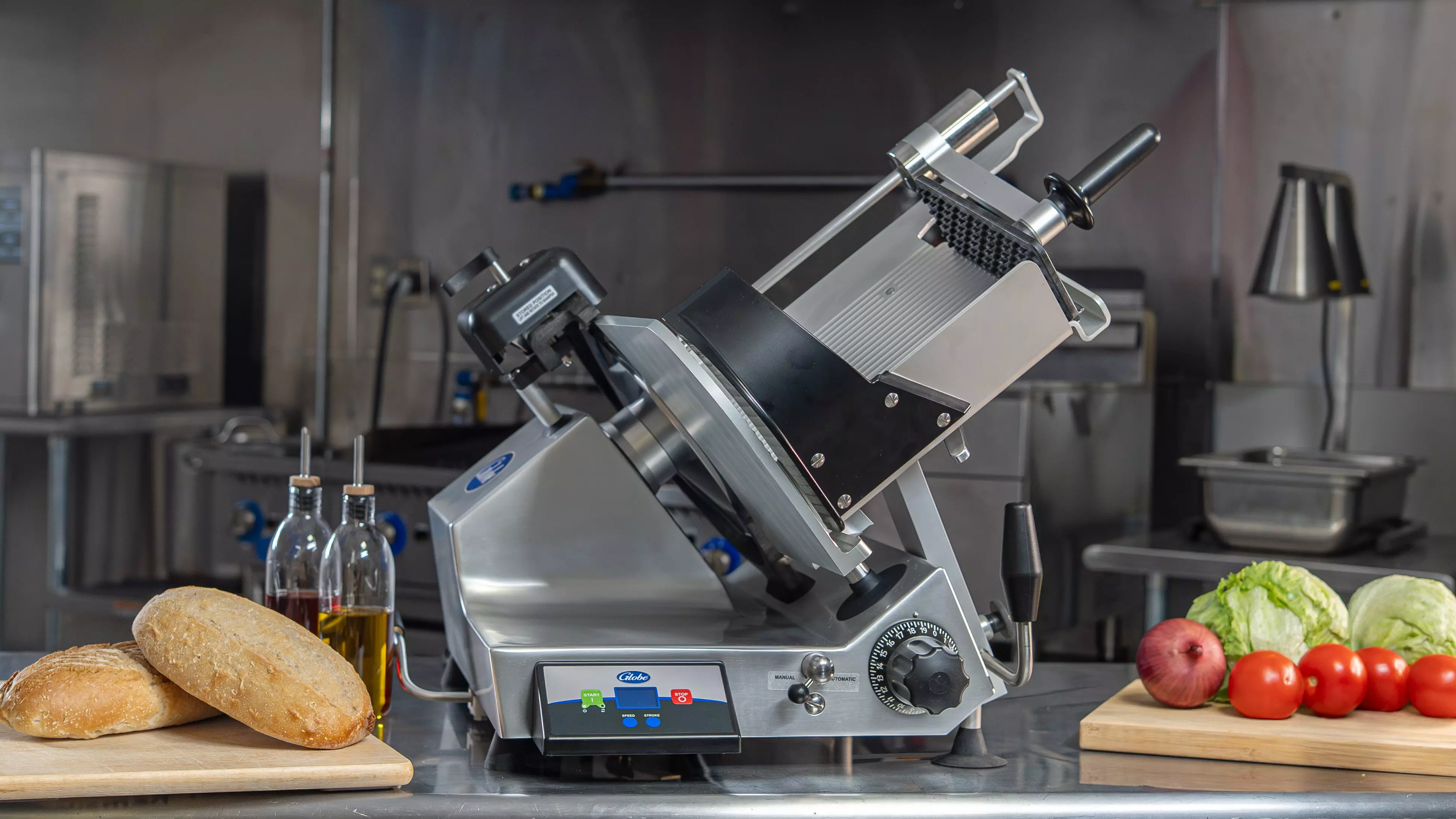 Globe commercial deli meat slicer on counter with bread, oil bottles, and fresh produce.