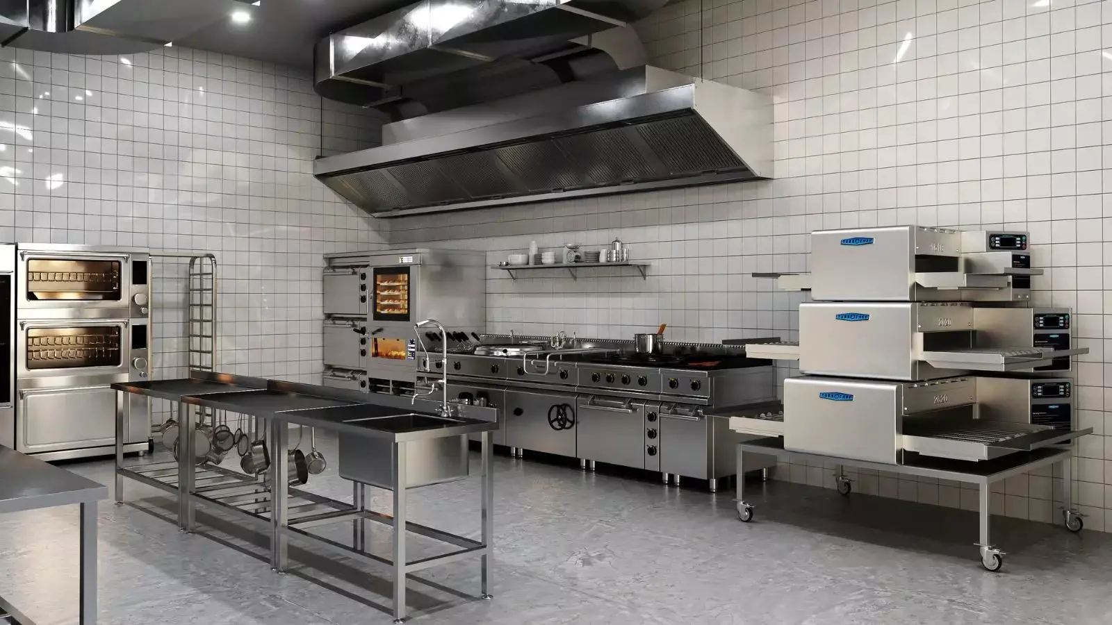 Commercial kitchen with ovens, stove, stainless steel tables, and shelves with dishes.