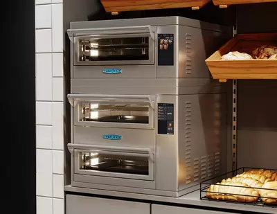 Stacked TurboChef stainless steel countertop ovens with digital touchscreens in a bakery display.